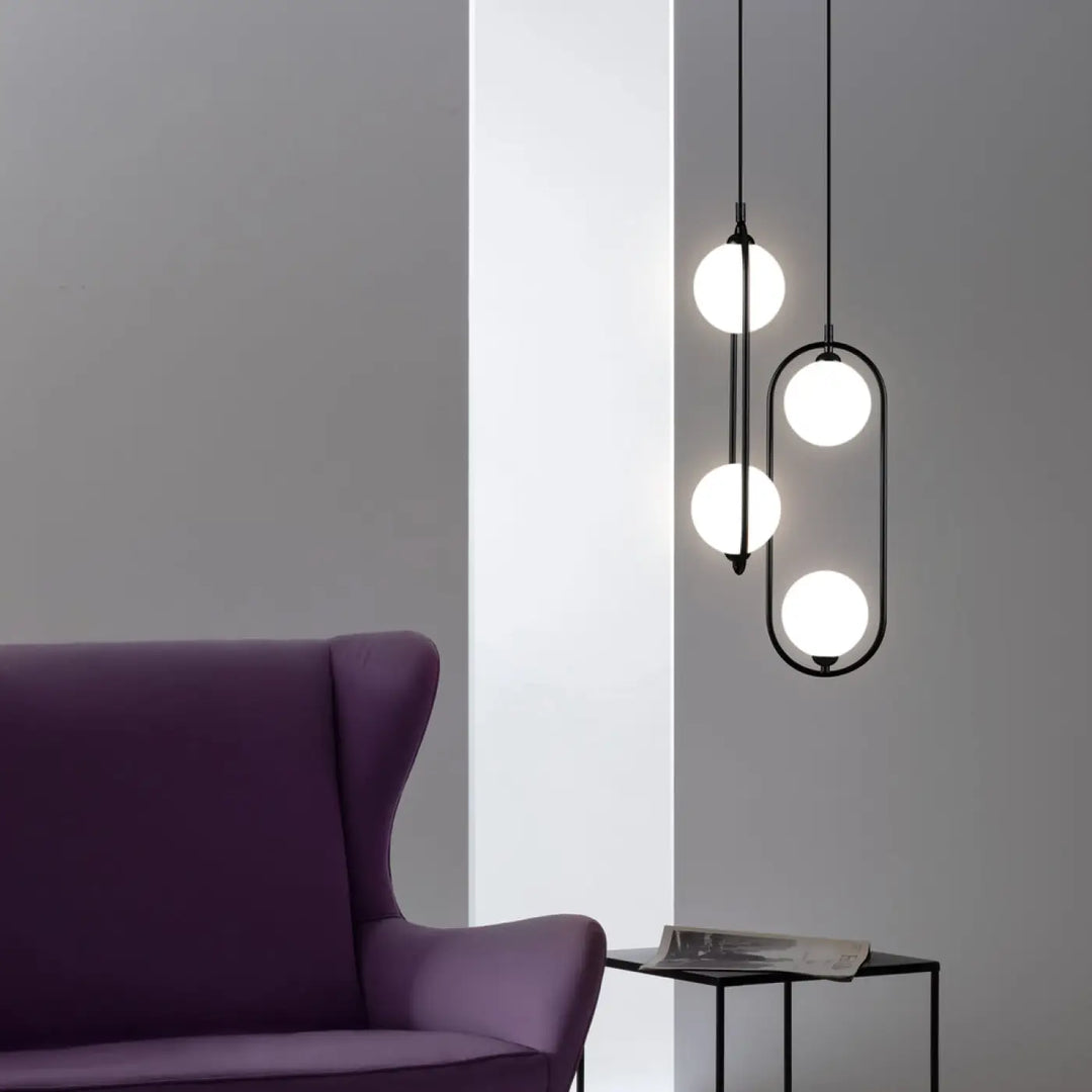 Suspension ring noire en métal avec quatre globes blancs lumineux en design vertical asymétrique art déco au-dessus d’un îlot