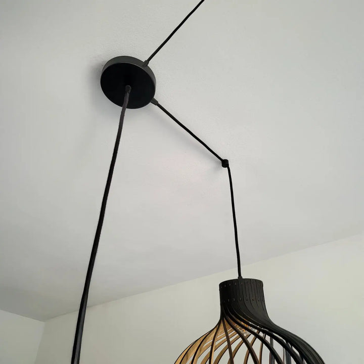 Suspension luminaire rinoz avec lames en bois courbées et accents en métal noir parfait pour cage descalier trois suspensions