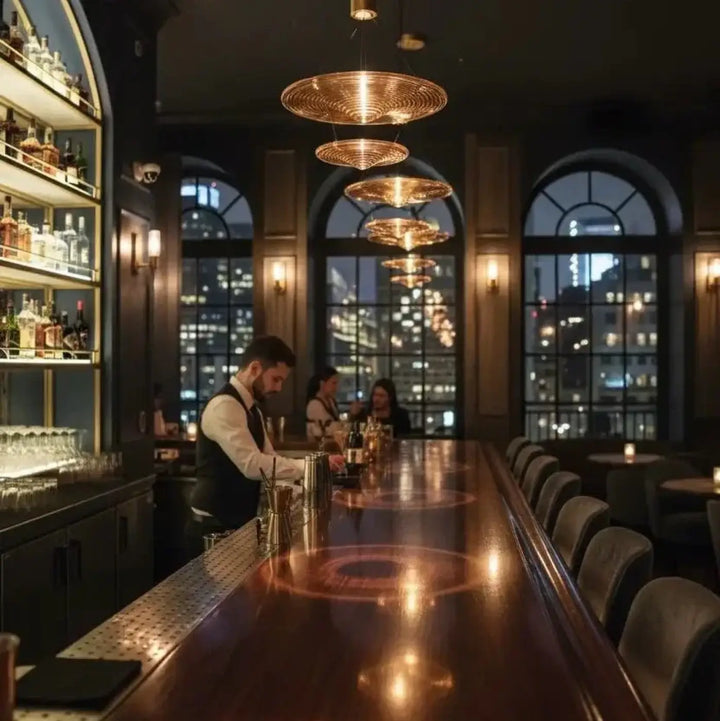 Suspension venise avec luminaires circulaires dorés en verre soufflé suspendus en cascade au-dessus d’un bar en bois polish